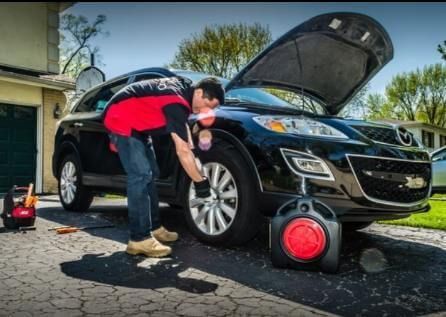 A man is changing a tire on a black car.
