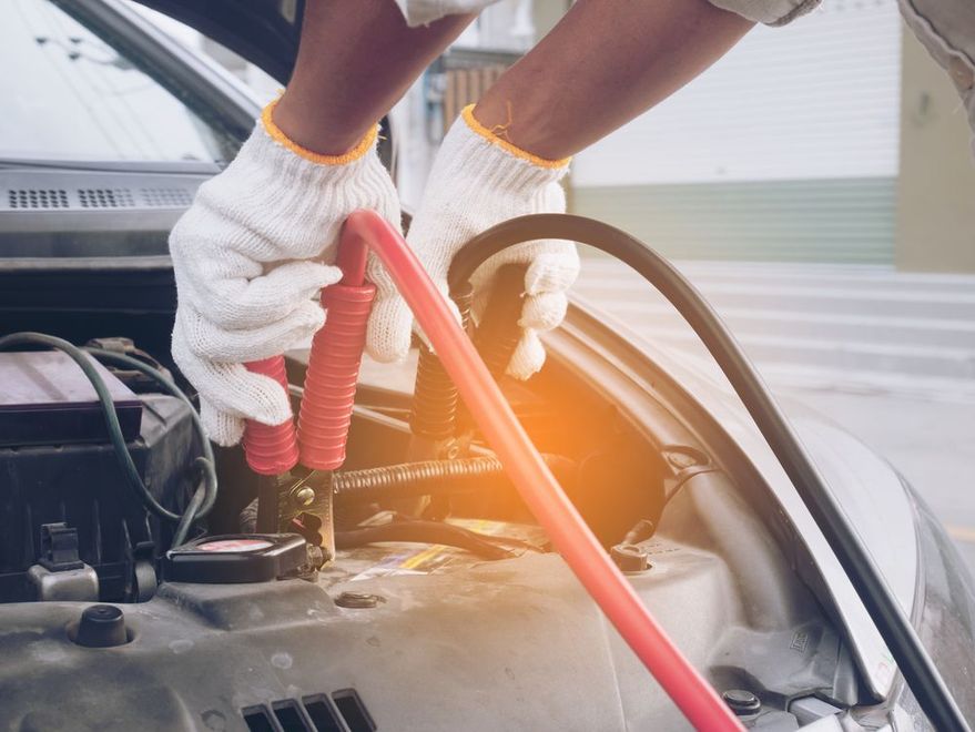 Man charging a car battery using jumper cables.