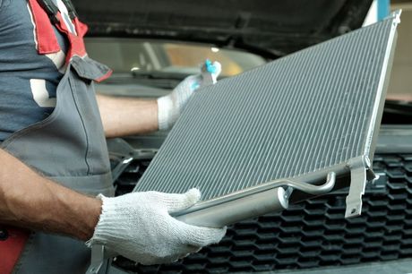 Mechanic holding a new car radiator.