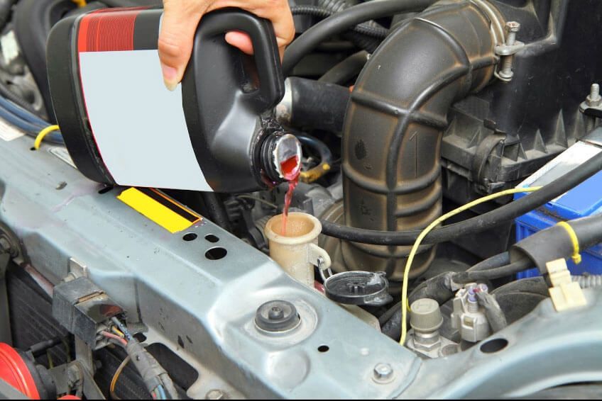 A person is pouring oil into a car engine.