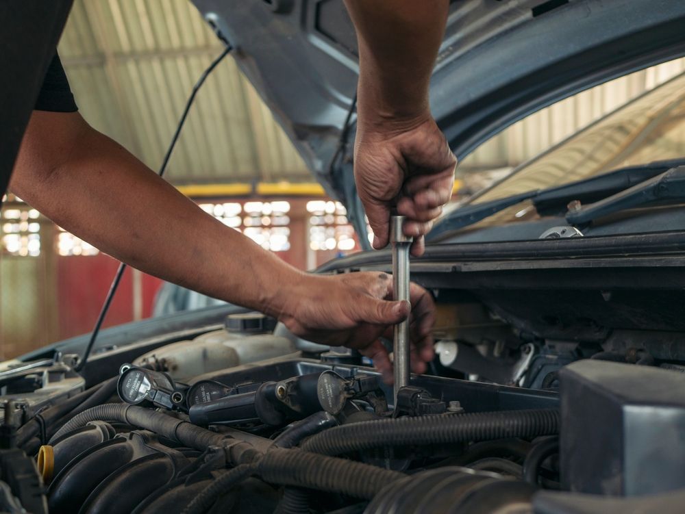 A man is working on the engine of a car with the hood open.