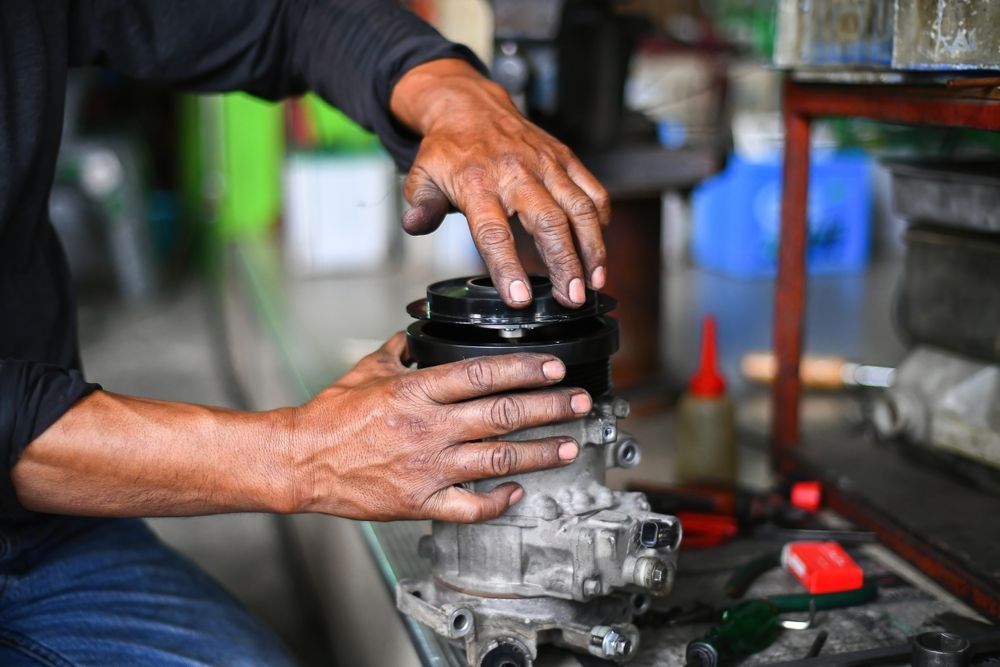 A man is working on a car starter in a garage.