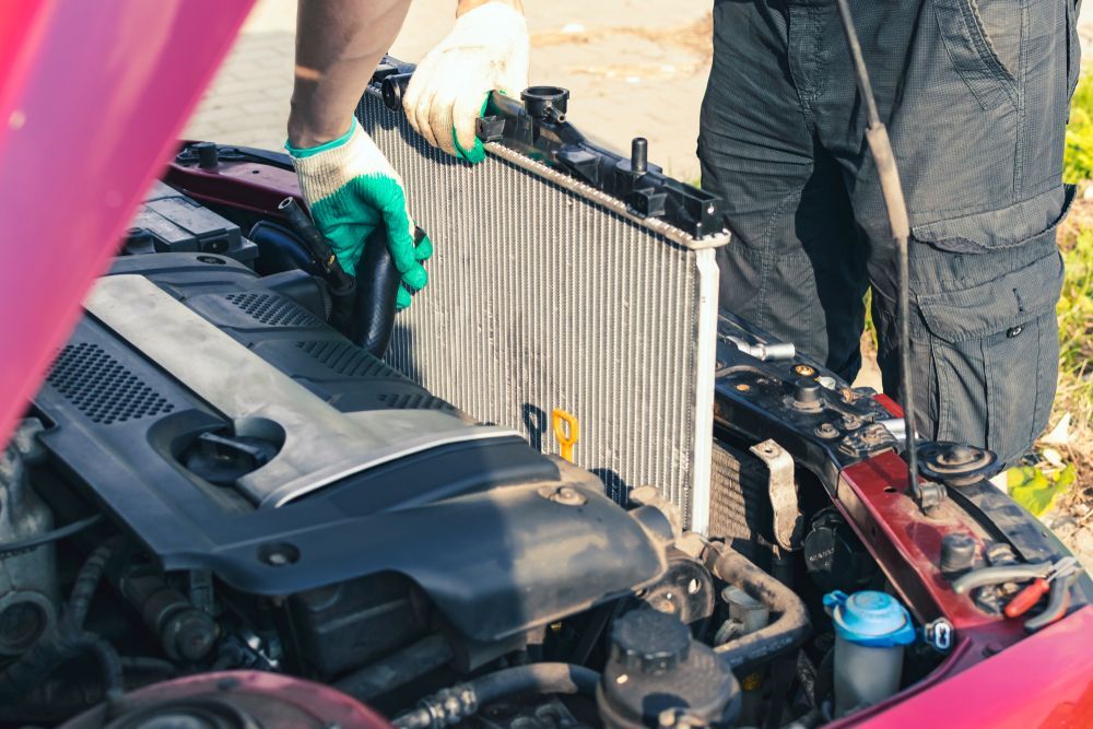A man is working on the radiator of a car.