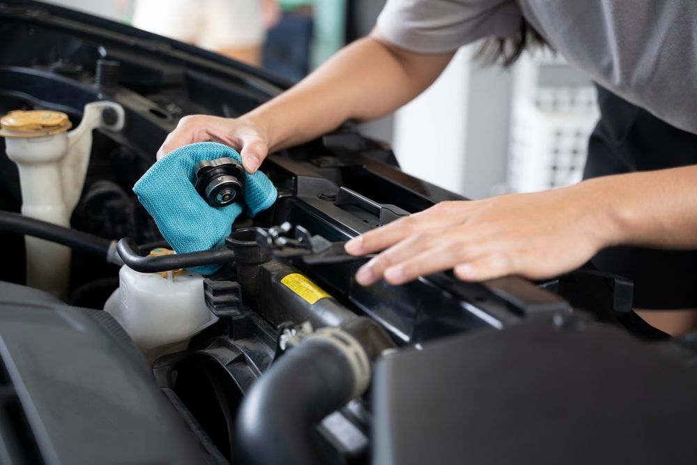 A person is cleaning the radiator of a car with a towel.