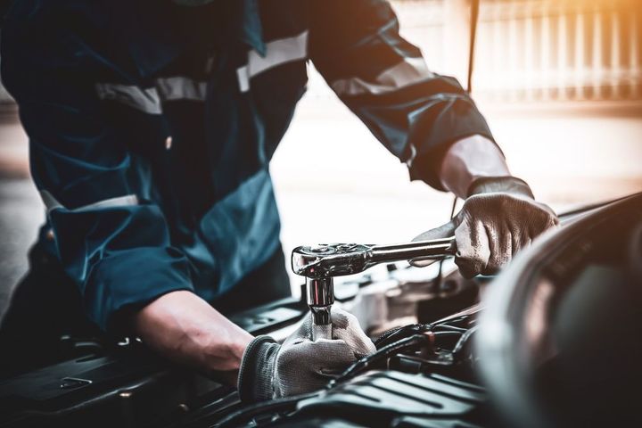 A mechanic is working on a car engine in a garage.