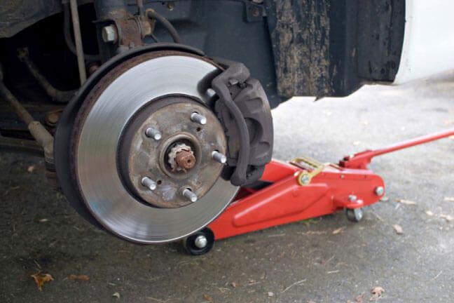 A car wheel is sitting on top of a red jack.
