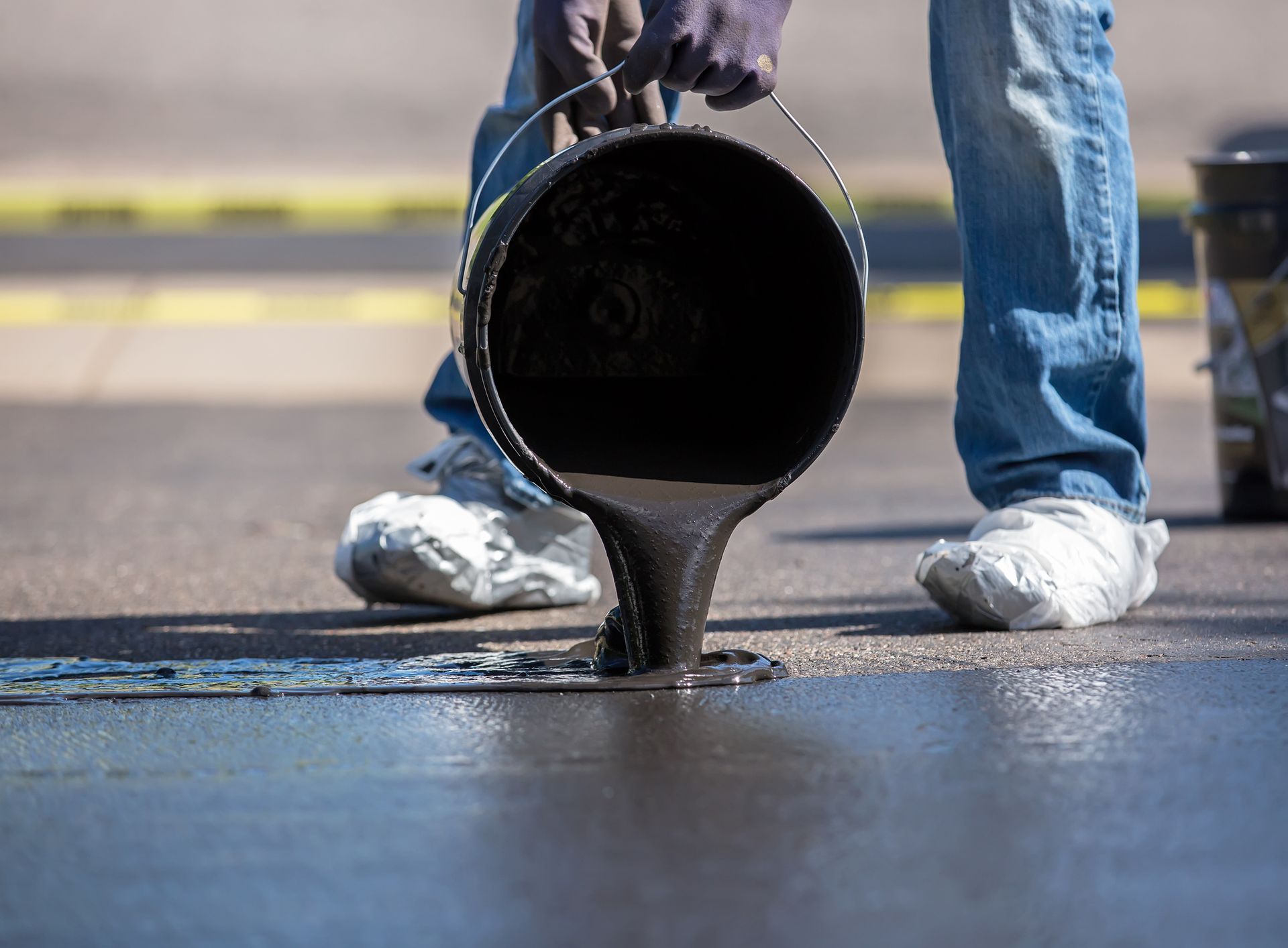 A close-up of sealcoating a driveway. A close-up of sealcoating a driveway.