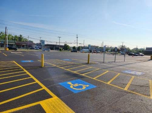 Empty accessible parking lot with blue disabled parking space, yellow striping, and a clear sky