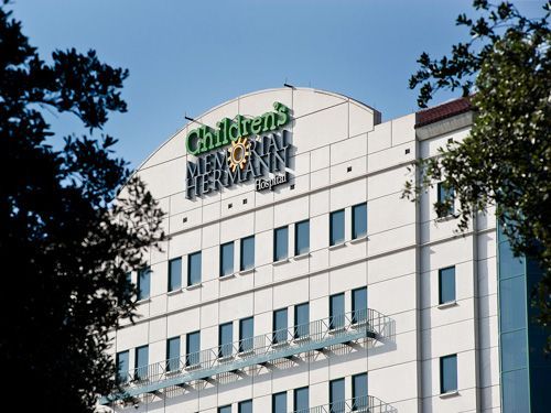 Children's Memorial Hermann Hospital, white building with green logo under a clear blue sky.