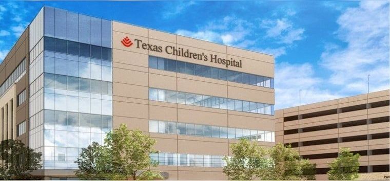 Texas Children's Hospital building with blue sky, trees, and parking garage.