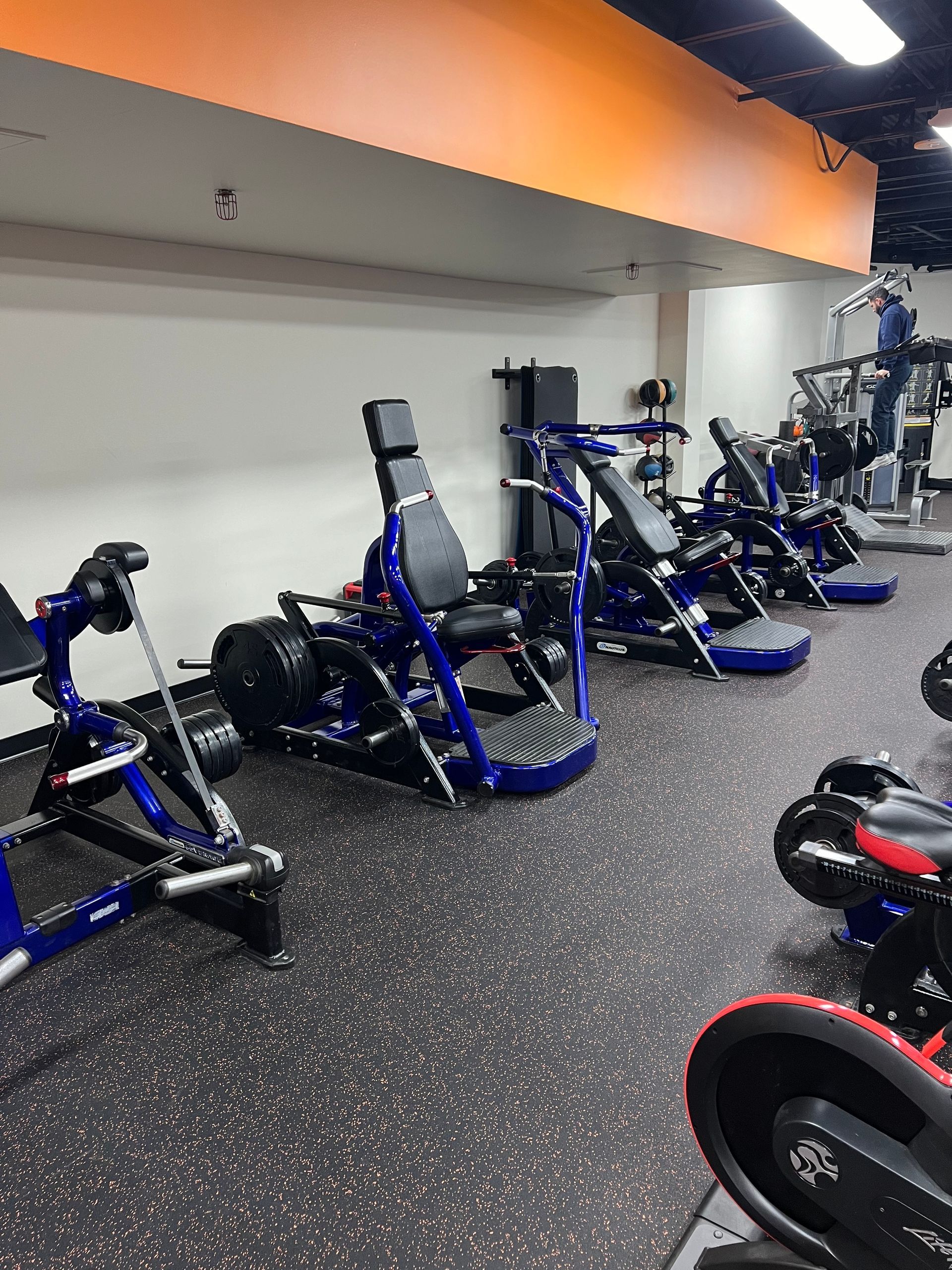 A gym filled with lots of exercise equipment and a person running on a treadmill.