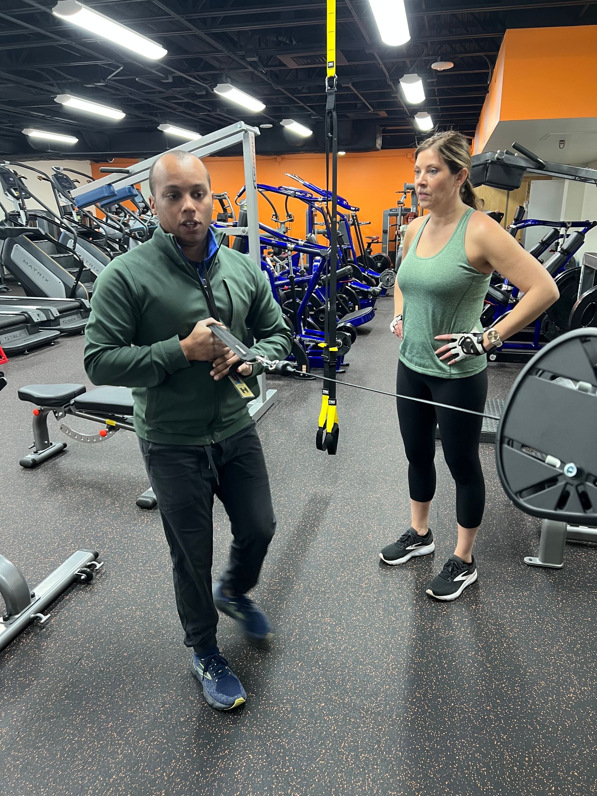 A man and a woman are standing in a gym talking to each other.