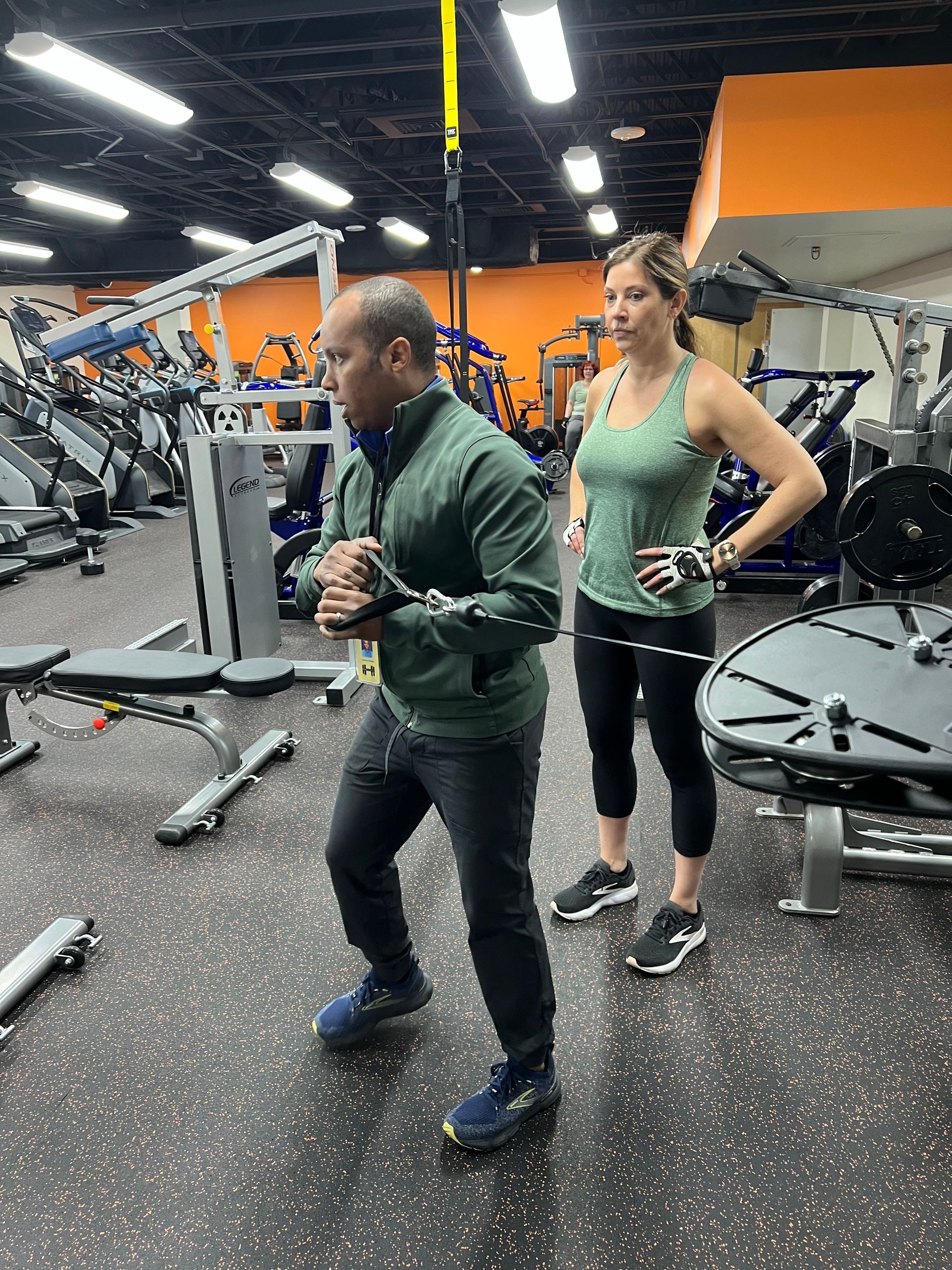 A man and a woman are working out in a gym.