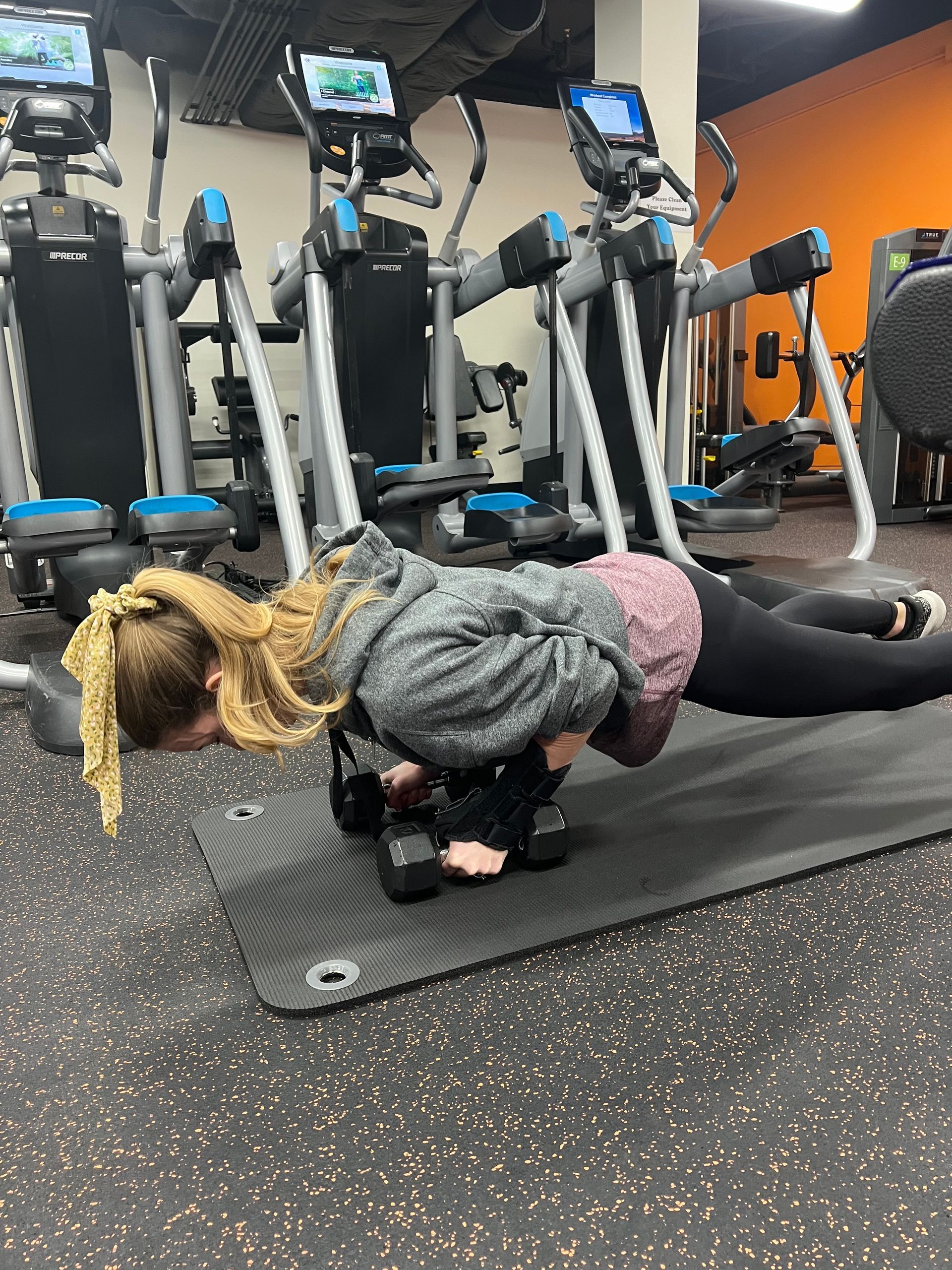 A woman is doing push ups on a mat in a gym.