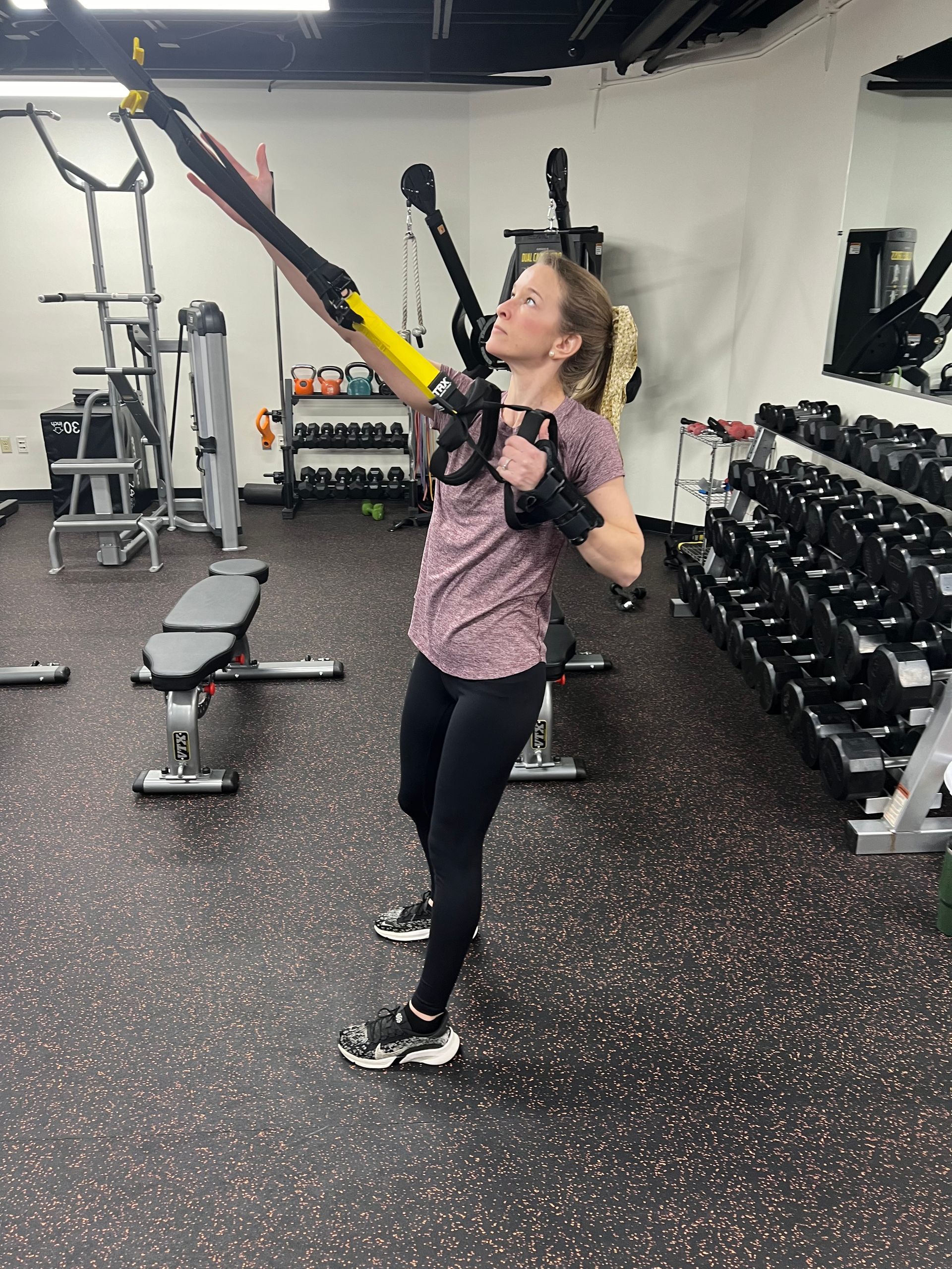 A woman is doing trx exercises in a gym.