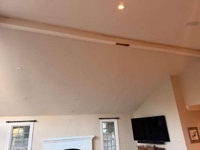Beige ceiling in a room with recessed lights and a mounted TV.
