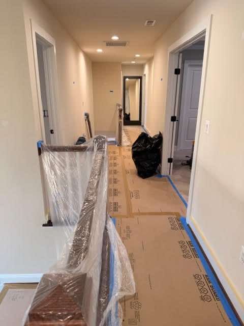 Hallway under construction with protective covering on the floor and staircase. Two doorways visible.