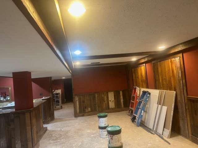 Basement under construction; wood paneling, red walls, and drywall.