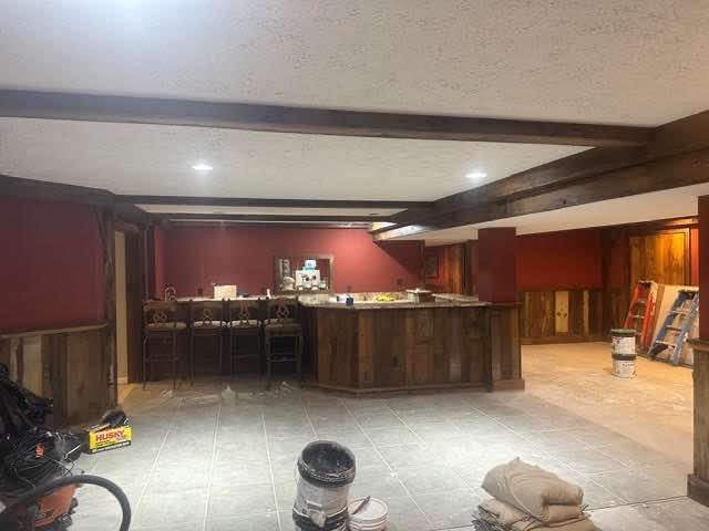 Basement bar under construction with red walls, wood accents, and concrete floor.