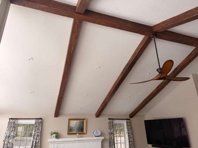 High ceiling with dark wood beams, white panels, recessed lights, and a ceiling fan.