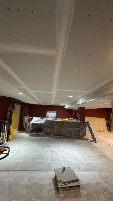 Construction site: Interior with drywall ceiling and bar area, tools scattered on floor.