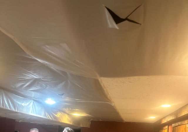 Plastic sheeting covering a ceiling with a hole and a decorative object.