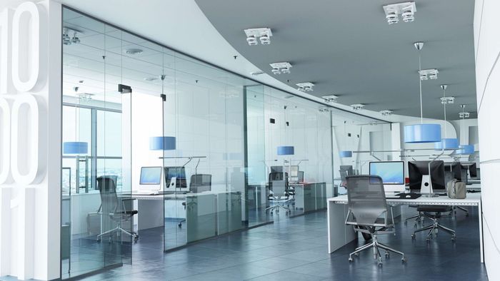 Modern office interior with glass walls, desks, and chairs. Blue accents and bright lighting.