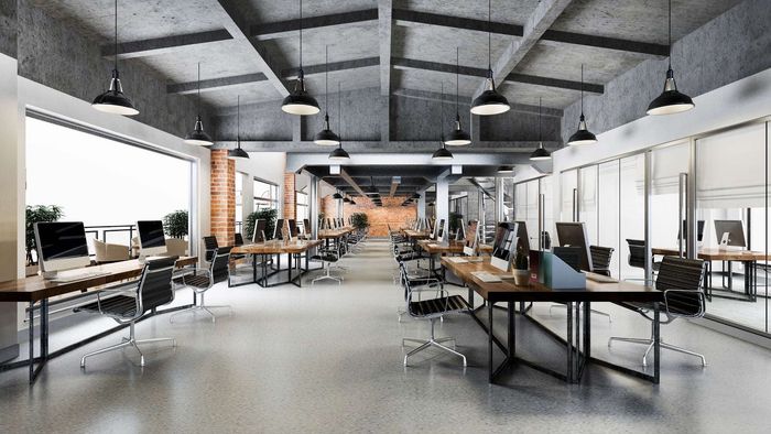 Modern office interior with workstations, concrete ceiling, and large windows.