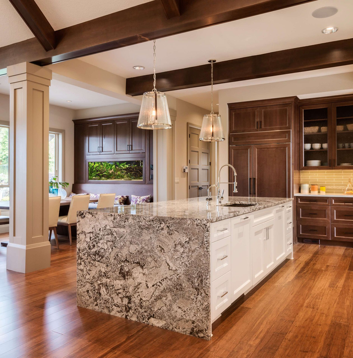 Kitchen with island, granite countertop, white cabinets, dark wood cabinets, hardwood floors, and pendant lights.