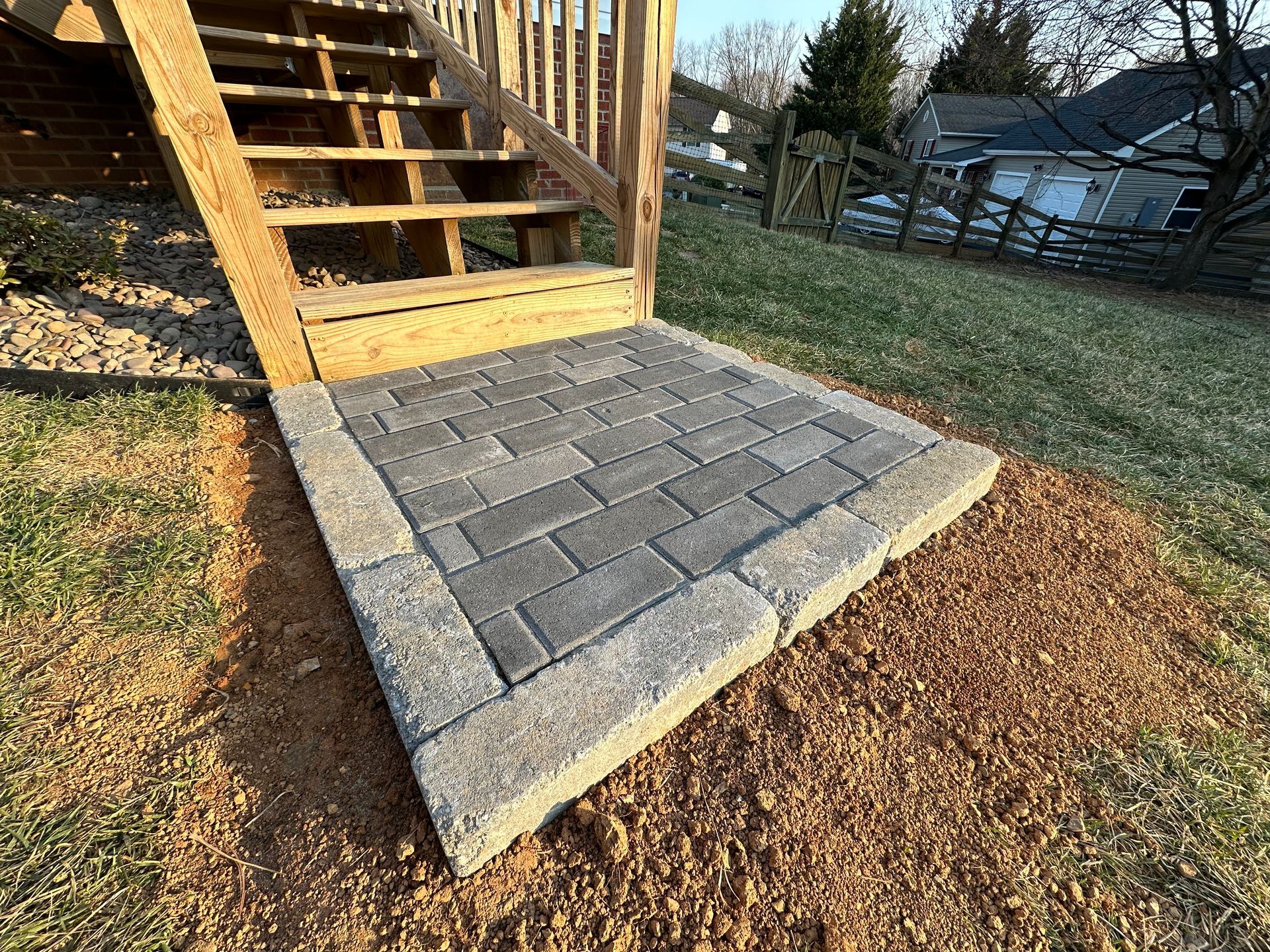 A brick walkway is being built next to a wooden deck.