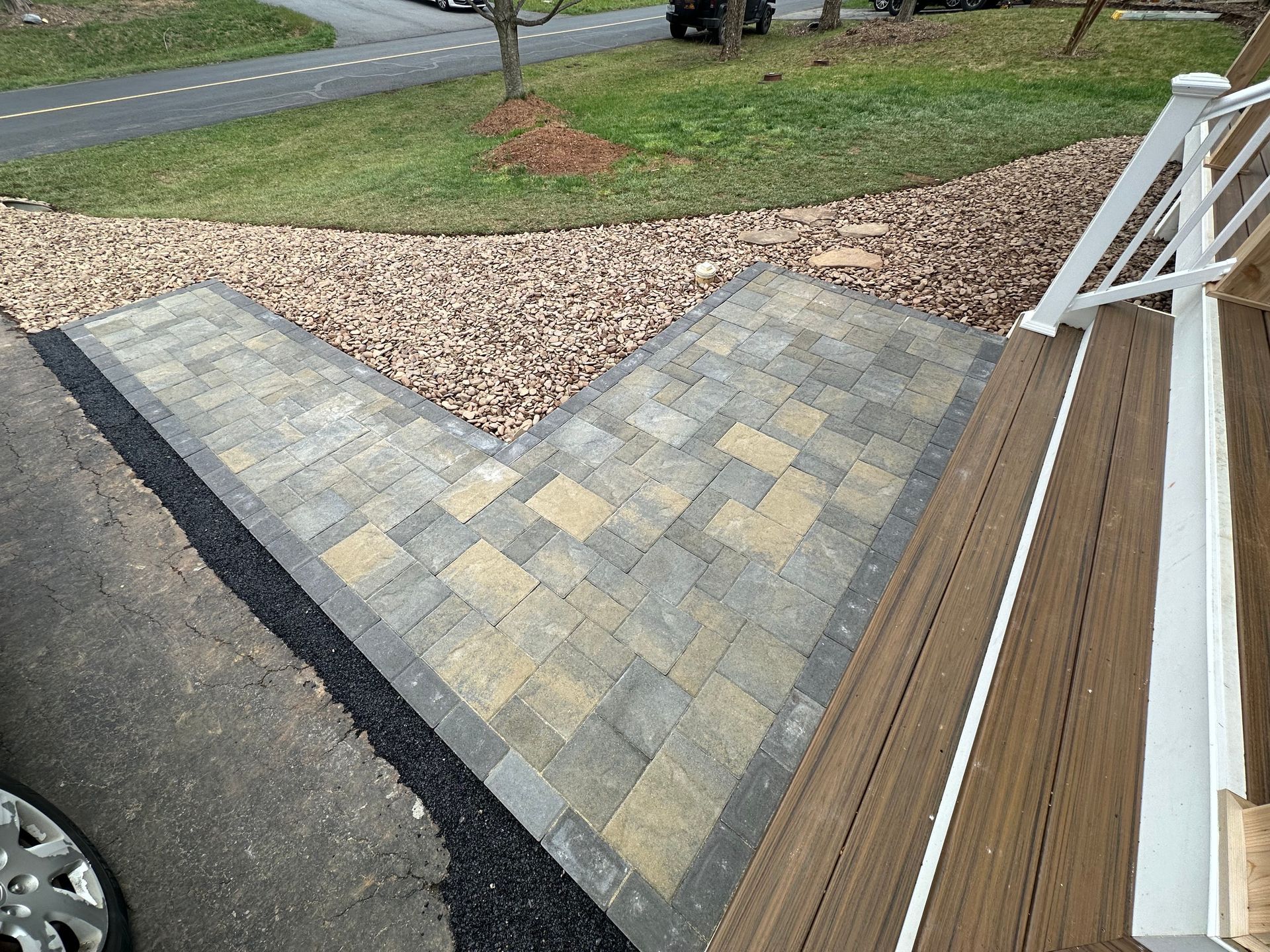 A wooden deck with a brick walkway leading to it.