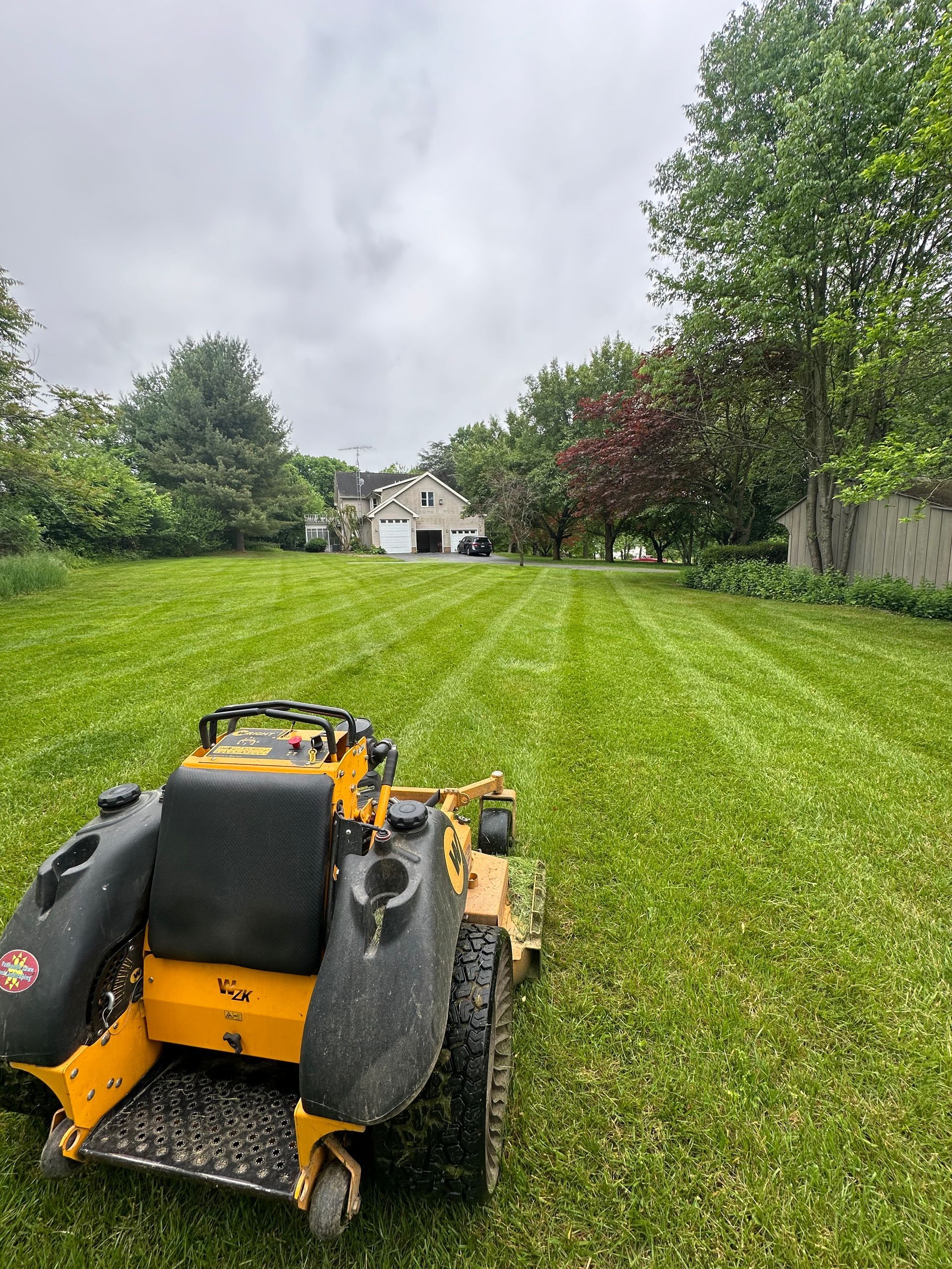 A yellow lawn mower is sitting in the middle of a lush green lawn.