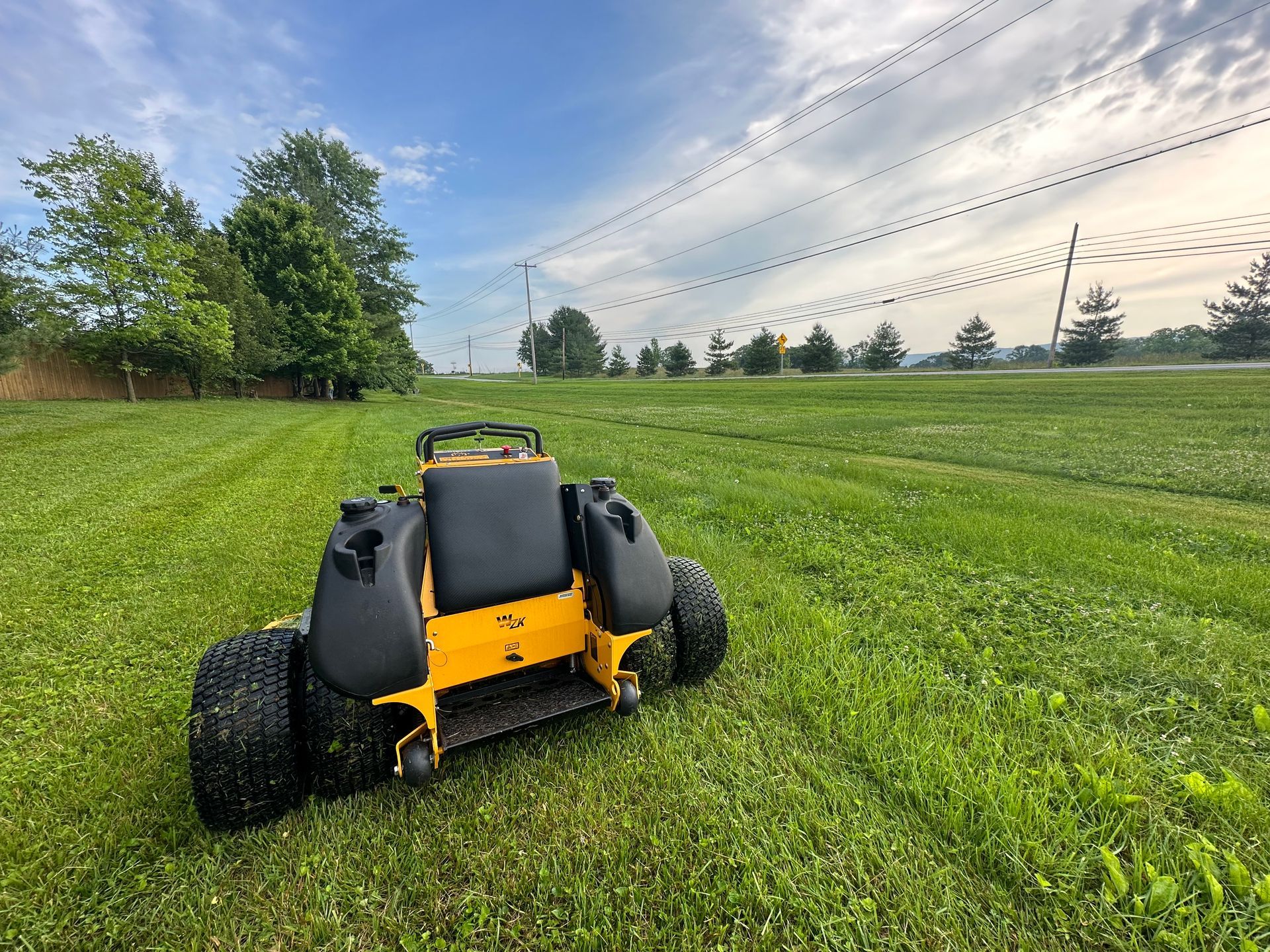 A yellow and black lawn mower is sitting in the middle of a lush green field.