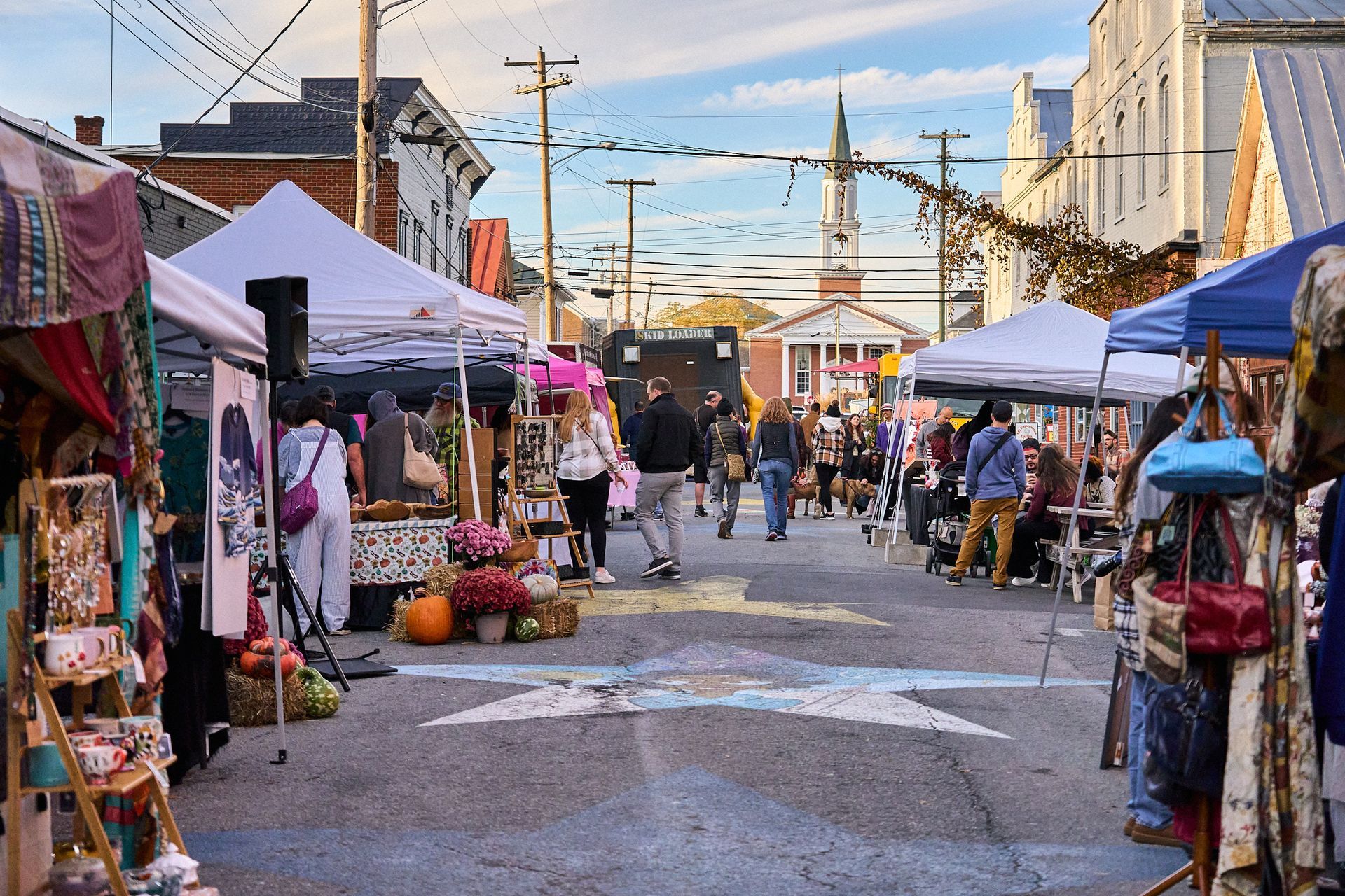 A street filled with lots of tents and people walking down it.