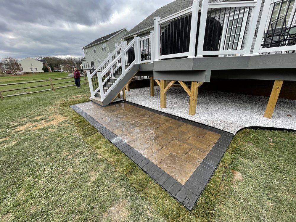 A large deck with stairs leading up to it is in the backyard of a house.