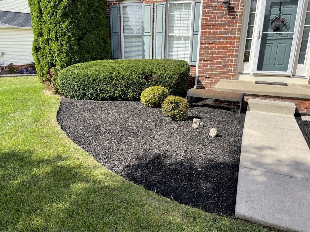 A brick house with a black mulch bed in front of it.