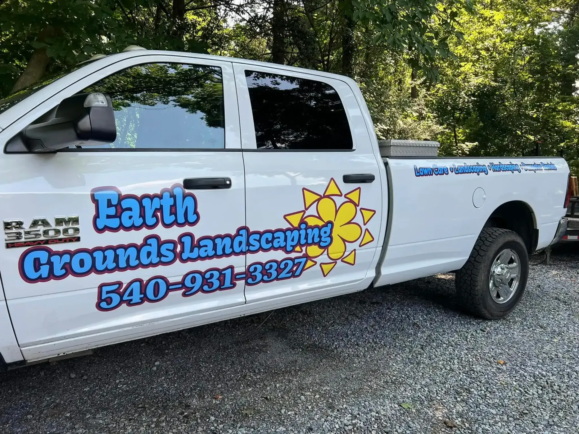 White landscaping pickup truck with Earth Grounds Landscaping logo parked on gravel drive White landscaping pickup truck with Earth Grounds Landscaping logo parked on gravel drive