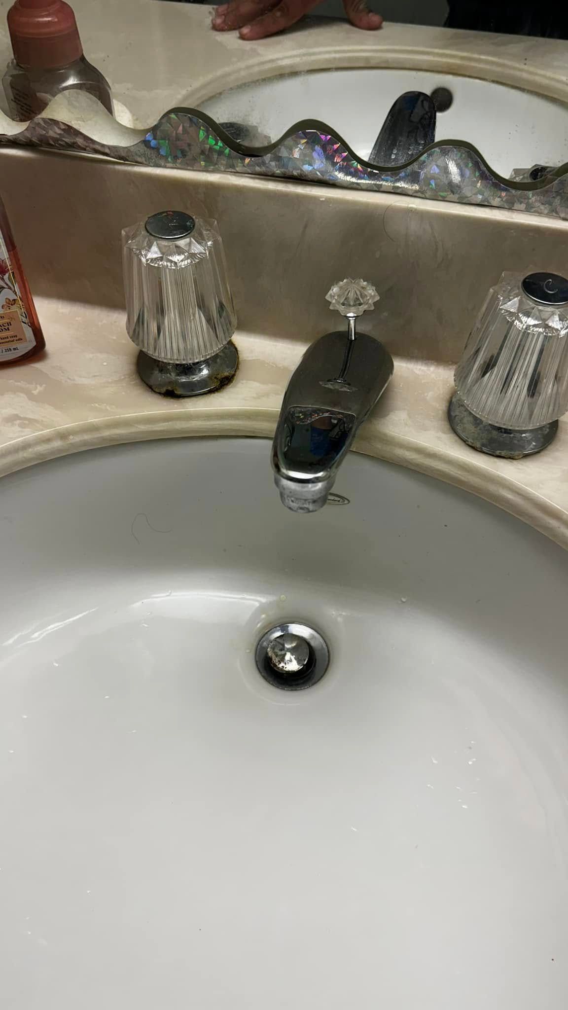 A bathroom sink with a faucet and a mirror.
