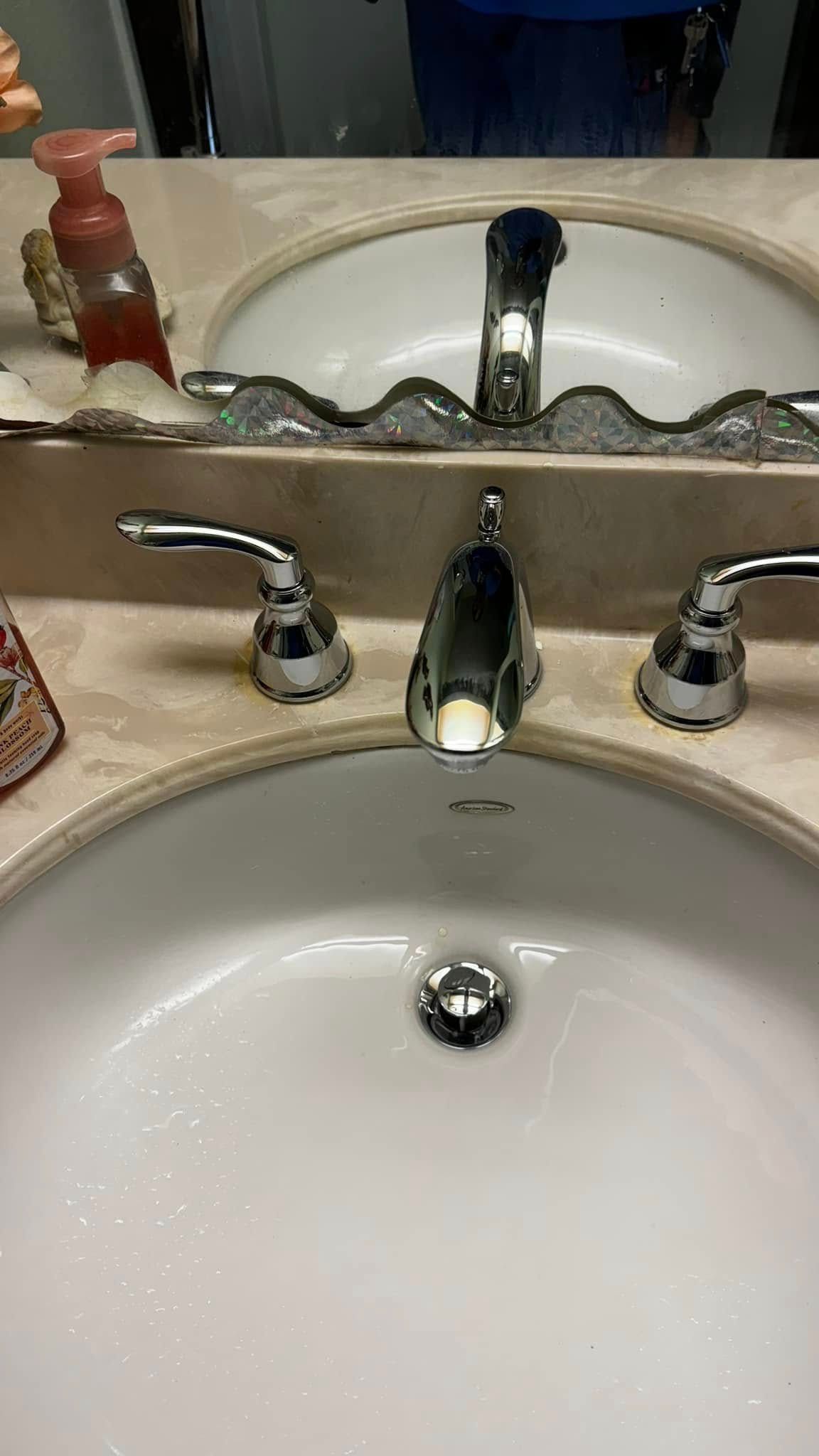 A bathroom sink with a faucet and a mirror.