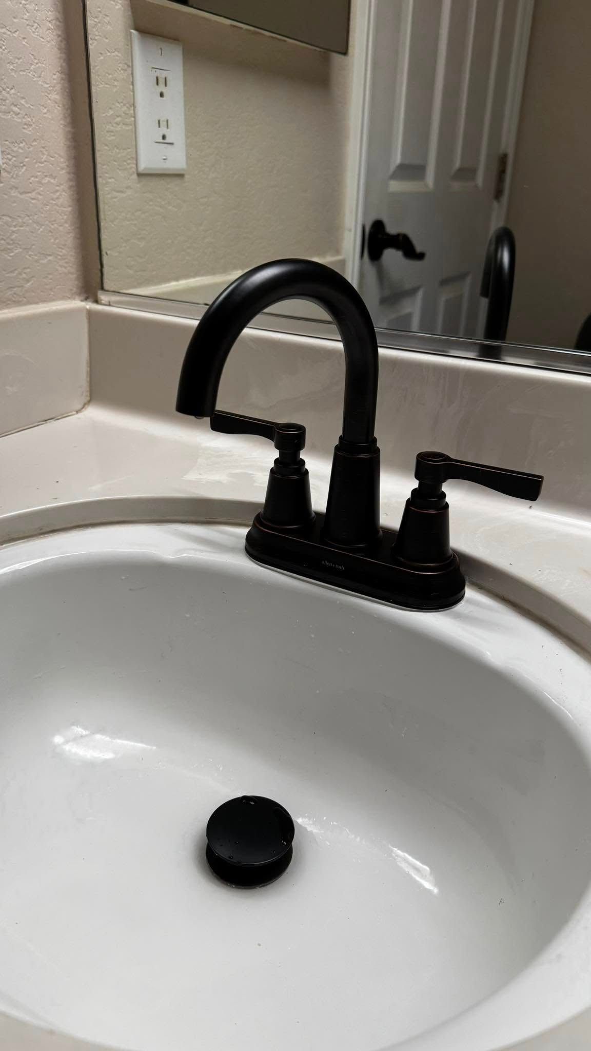 A bathroom sink with a black faucet and a mirror.