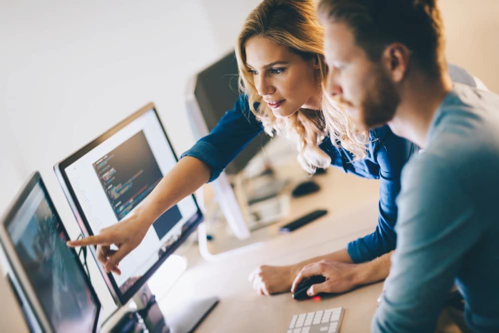 A Man And A Woman Are Looking At A Computer Screen — ActiveCo.IT in Taree, NSW