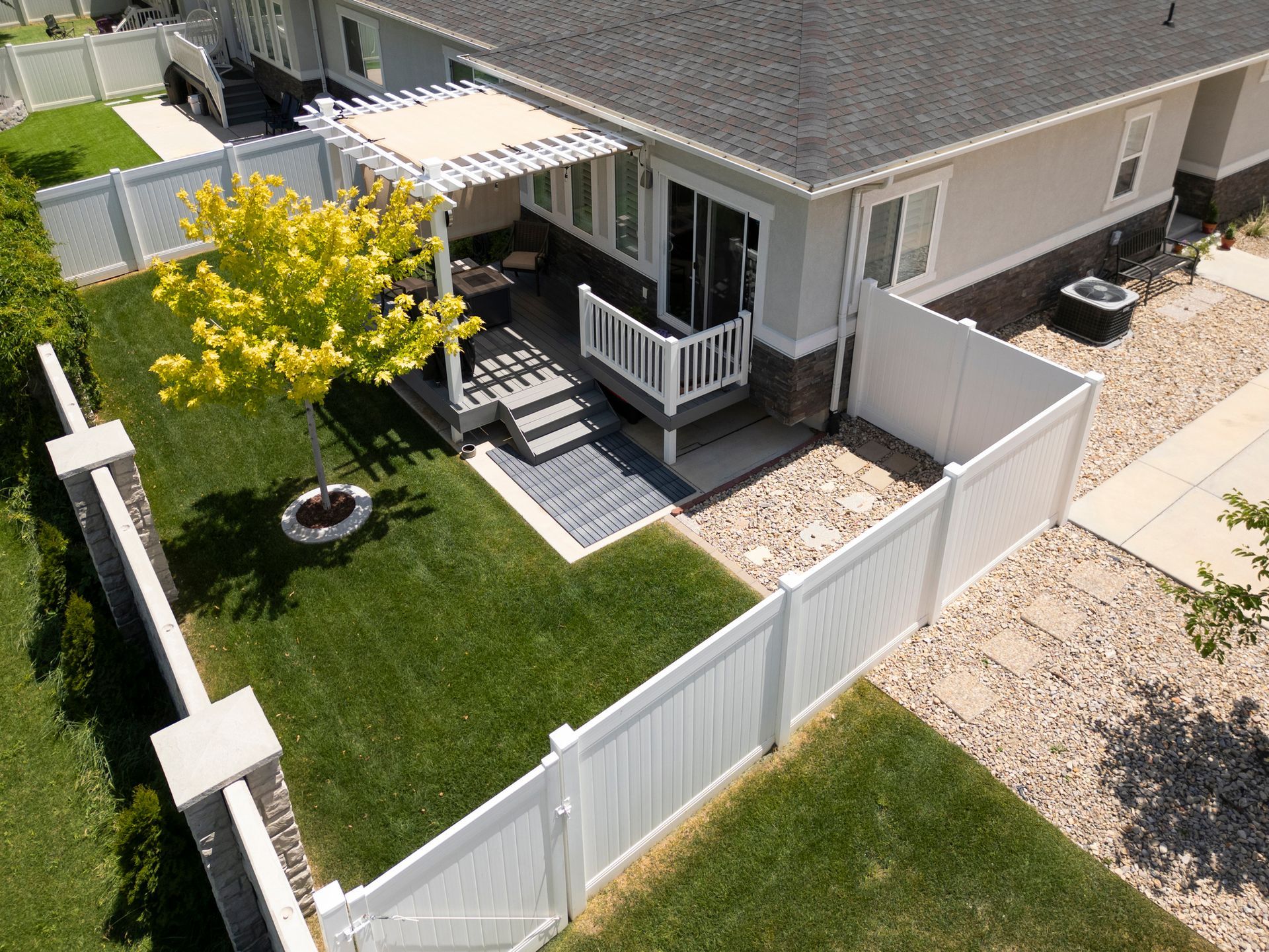 An aerial view of a house with a white fence and a pergola.