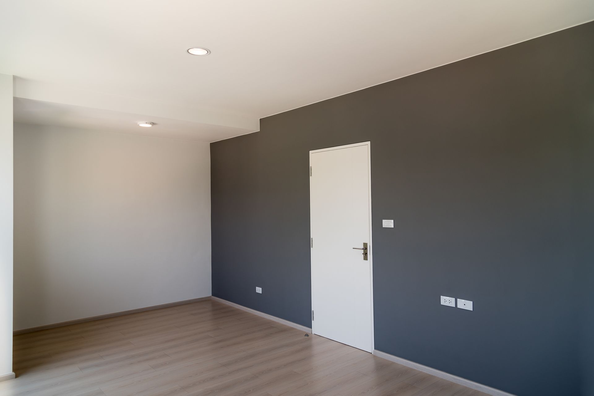 An empty room with gray walls and a white door.