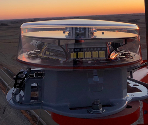 A close up of a light with a sunset in the background