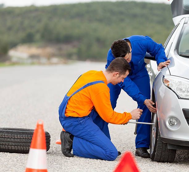 Two men are changing a tire on a car