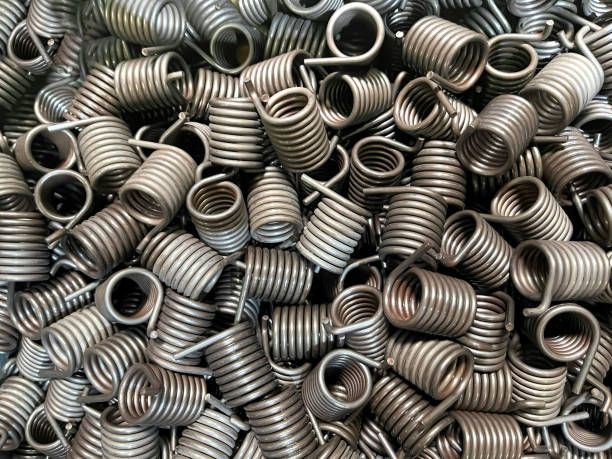 Batch of torsion springs shown from above with detailed spiral coils and textured metal surfaces