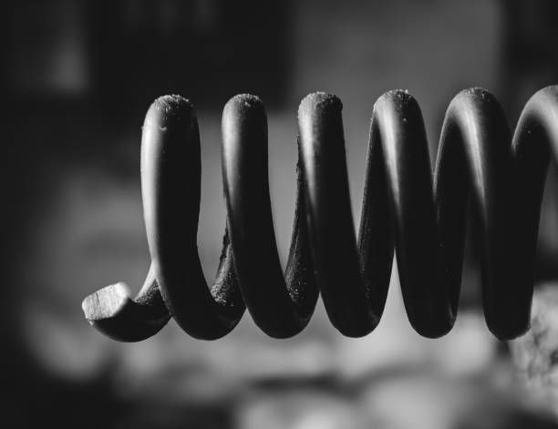 Close-up of a black metal compression spring with a broken end in soft focus.