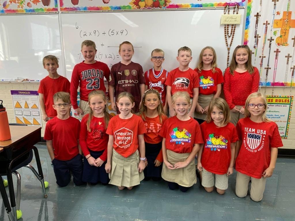 Group of students wearing red outfits in a classroom.