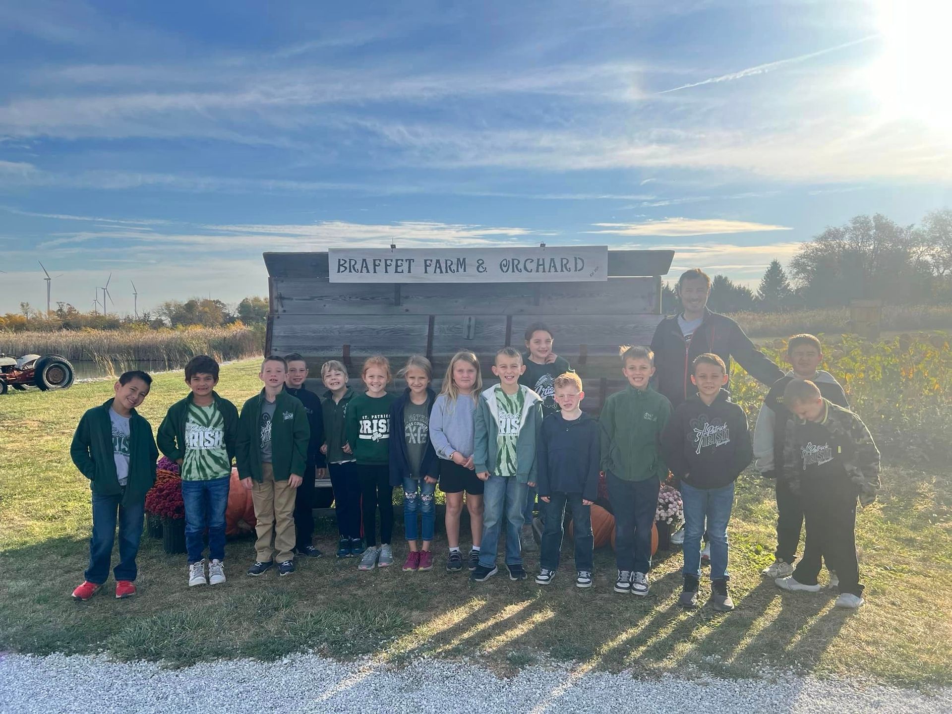 Children in green jackets stand in front of a 