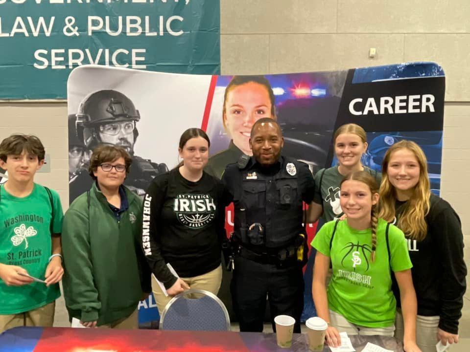 Group of students with a police officer at a career fair booth for law and public service.